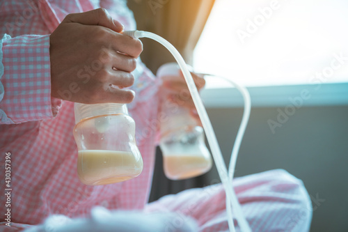 Automatic breast pump, mother's breasts milk is the most healthy food for newborn baby. Happy mother with babies at bed room ,home