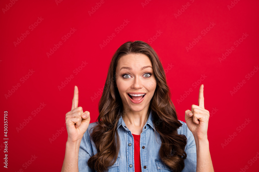Portrait of attractive amazed cheerful wavy-haired girl demonstrating up ad offer isolated over vibrant red color background Portrait of attractive amazed cheerful wavy-haired girl demonstrating up ad offer isolated over vibrant red color background