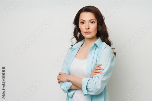 Young woman portrait. Adorable brunette in a sweater looking at the camera with her arms crossed.