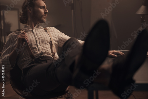 the scene of a brutal detective thinking about something in his office, he is wearing a striped shirt, classic pants and suspenders, sitting in a chair with his feet on the table