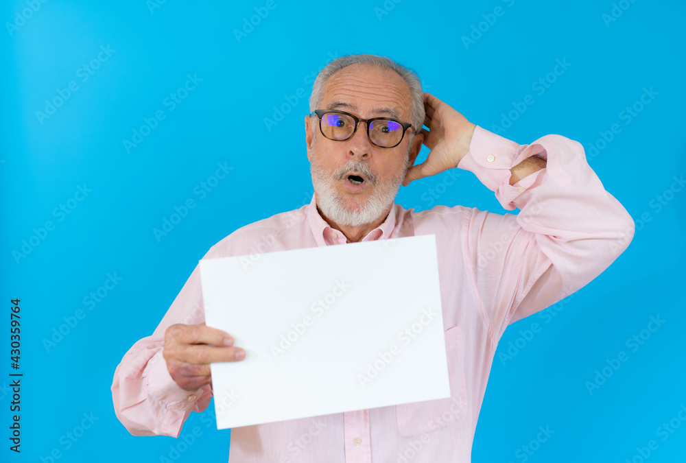 Portrait of a senior man surprised holding blank space paper over blue background Portrait of a senior man surprised holding blank space paper over blue background