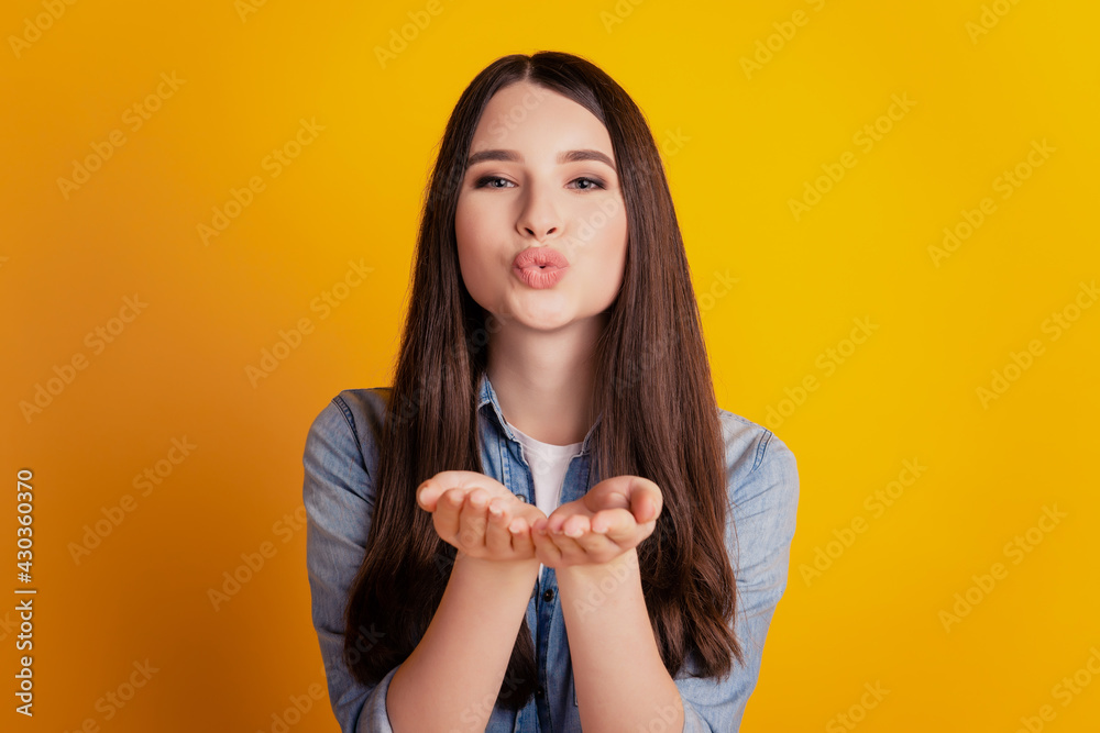 Portrait of a lovely adorable girlfriend sending air kiss on yellow background