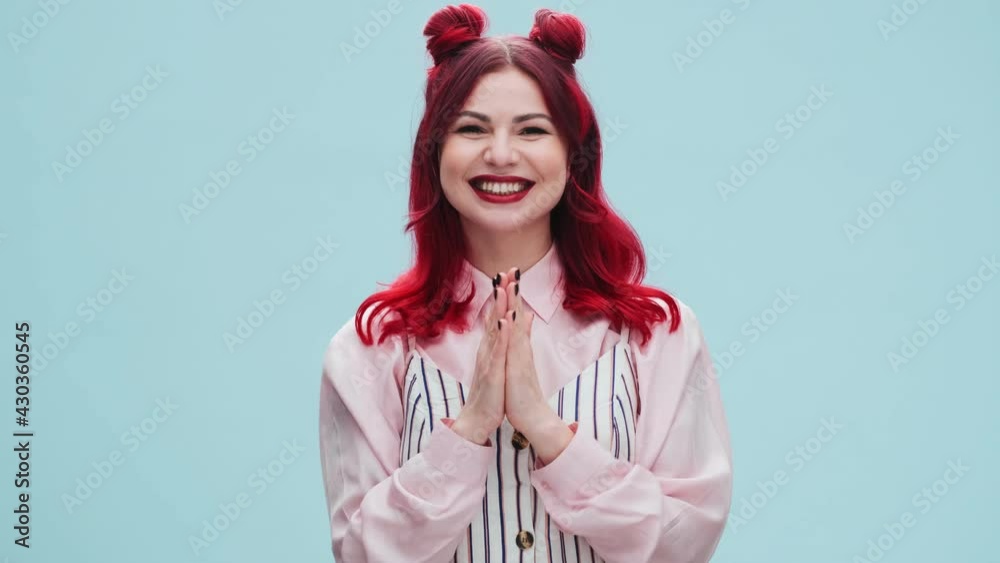 A happy cheerful woman with red lips is looking to the camera standing isolated over a blue wall in the studio A happy cheerful woman with red lips is looking to the camera standing isolated over a blue wall in the studio