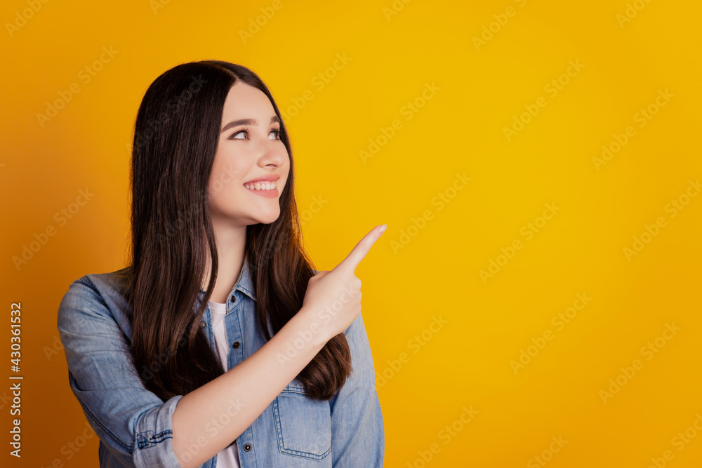 Portrait of positive girl point finger copyspace look side isolated over yellow color background Portrait of positive girl point finger copyspace look side isolated over yellow color background