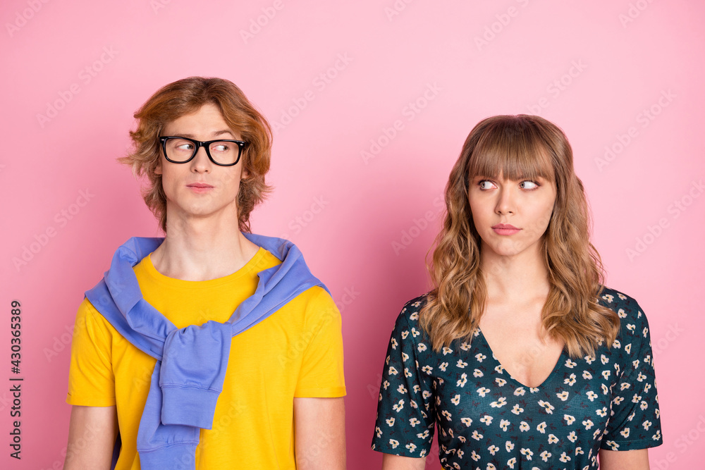 Portrait of attractive suspicious couple looking at each other meet date isolated over pink pastel color background Portrait of attractive suspicious couple looking at each other meet date isolated over pink pastel color background