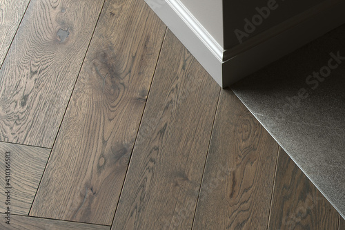 Room corner, three different textures: grey wall, natural oak wood floor, stone dark grey tiles photo