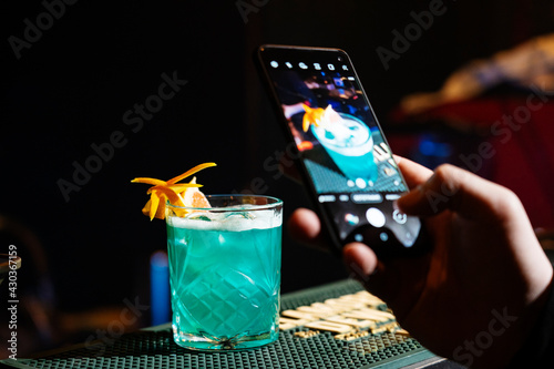 Male hand taking photo of Two fresh mojito cocktails with cell, mobile phone.