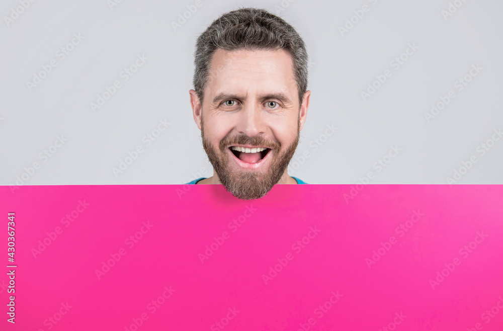 happy mature bearded man behind blank pink paper banner with copy space for info, sale happy mature bearded man behind blank pink paper banner with copy space for info, sale