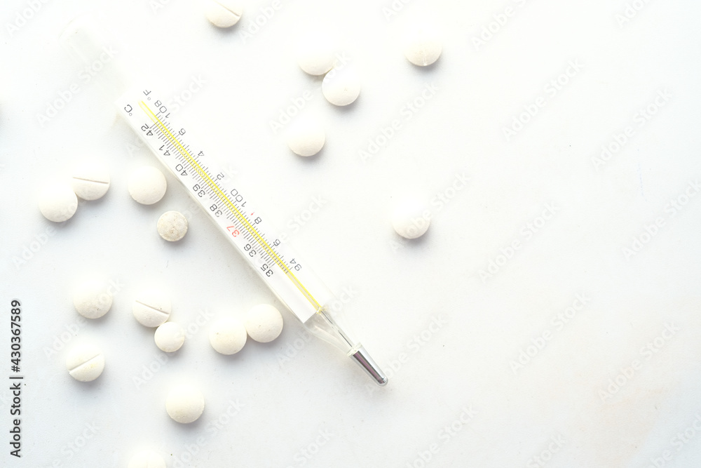 medical thermometer and pills on white texture background medical thermometer and pills on white texture background