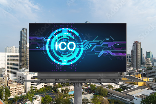 ICO hologram icon on billboard over panorama city view of Bangkok at day time. The hub of blockchain projects in Southeast Asia. The concept of initial coin offering, decentralized finance