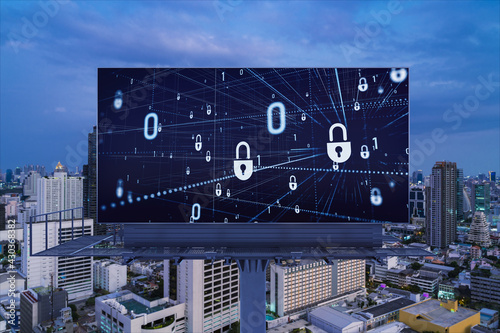 Padlock icon hologram on road billboard over panorama city view of Bangkok at night to protect business, Southeast Asia. The concept of information security shields.