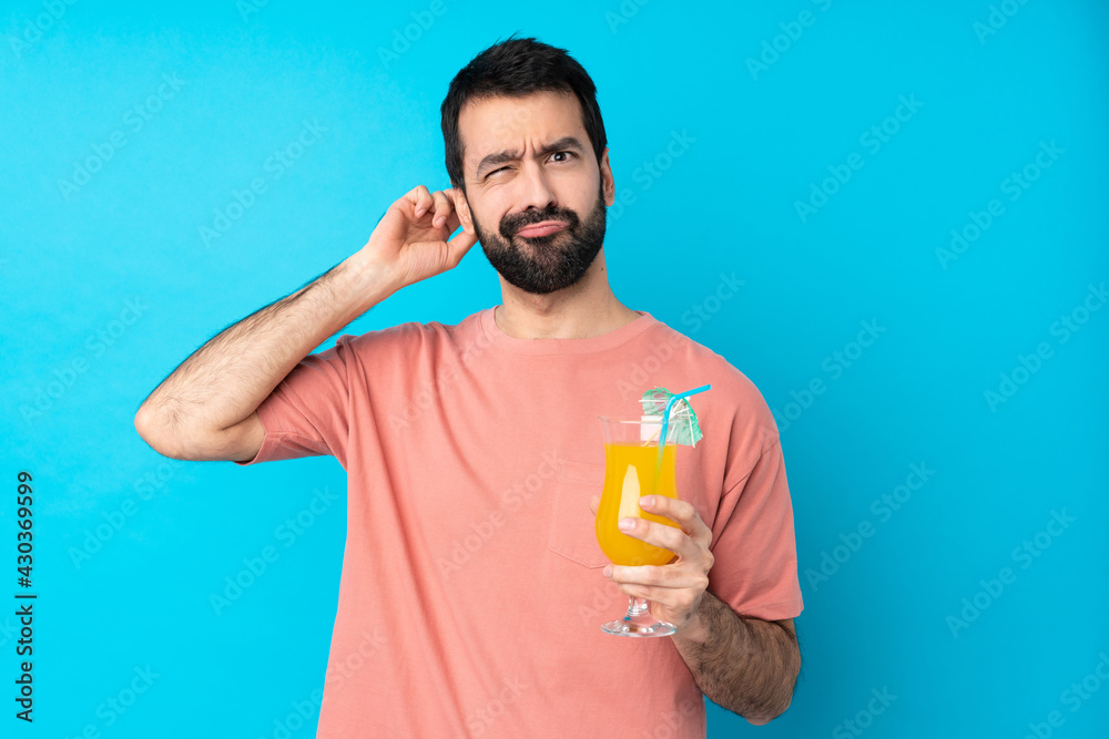 Young man over holding a cocktail over isolated blue background having doubts Young man over holding a cocktail over isolated blue background having doubts