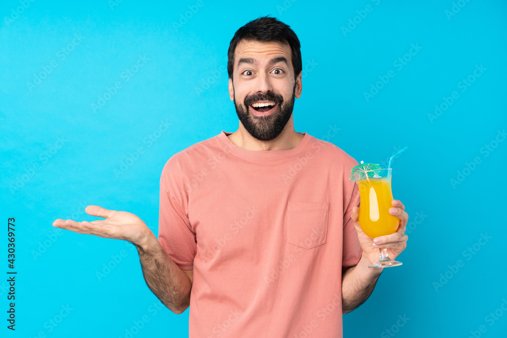 Young man over holding a cocktail over isolated blue background with shocked facial expression Young man over holding a cocktail over isolated blue background with shocked facial expression