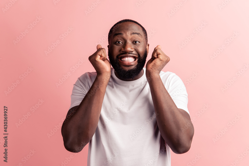 Fototapeta premium Photo of winner man hold fists toothy smile on pink background