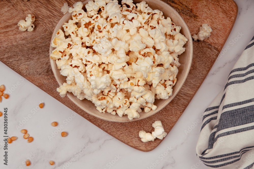 Ceramic bowl on a rustic wooden board with popcorn