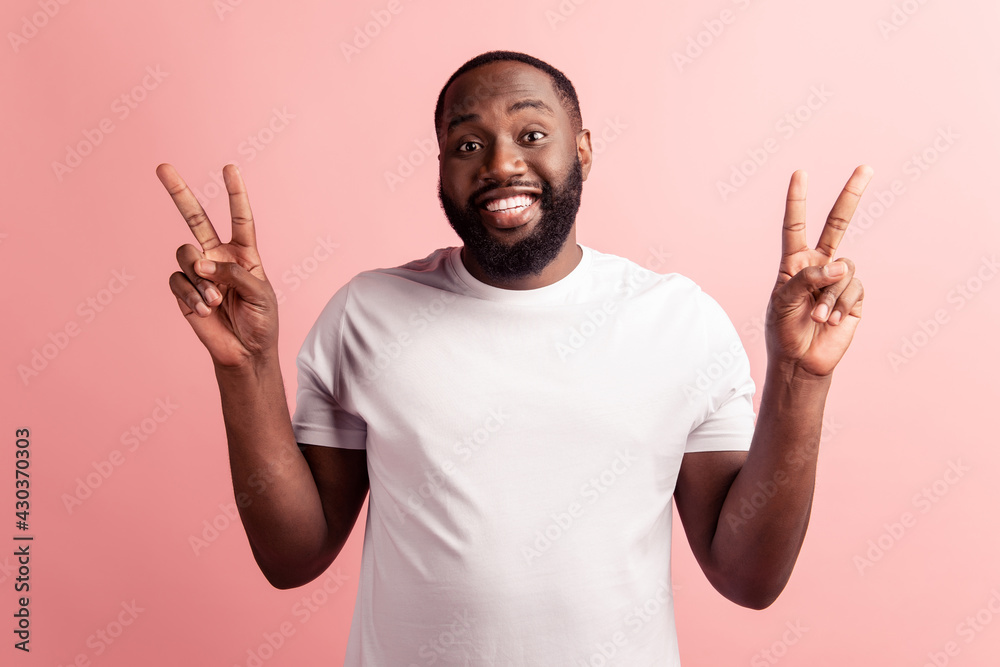 smiling dark-skinned young man showing two fingers up smiling dark-skinned young man showing two fingers up