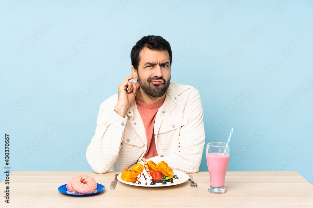 Man at a table having breakfast waffles and a milkshake having doubts Man at a table having breakfast waffles and a milkshake having doubts