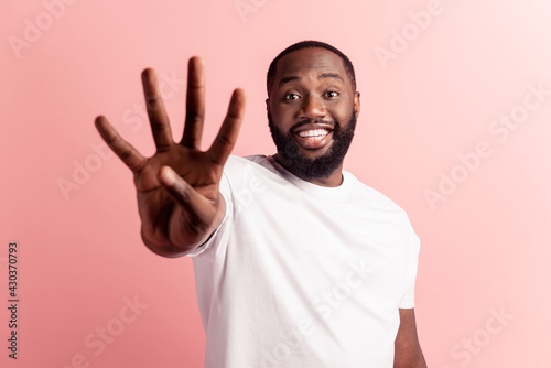 Closeup portrait of young handsome man giving a four fingers sign on pink wall photo