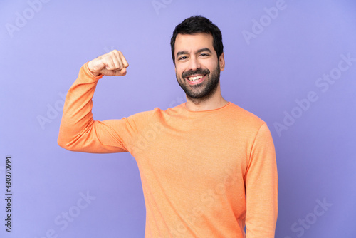 Caucasian handsome man over isolated purple background doing strong gesture © luismolinero