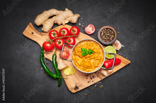 Fototapeta Naklejka Na Ścianę i Meble -  Pot of Traditional Chicken Curry and spices on wooden servig cutting board