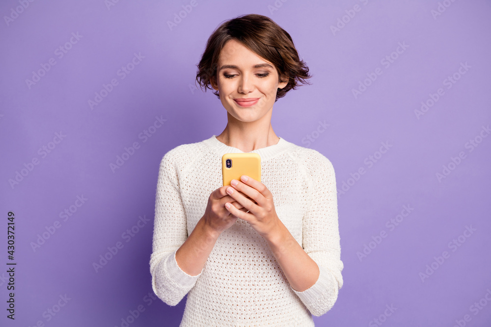 Photo portrait of cheerful happy brunette girl wearing sweater smiling with smartphone isolated on pastel purple color background Photo portrait of cheerful happy brunette girl wearing sweater smiling with smartphone isolated on pastel purple color background