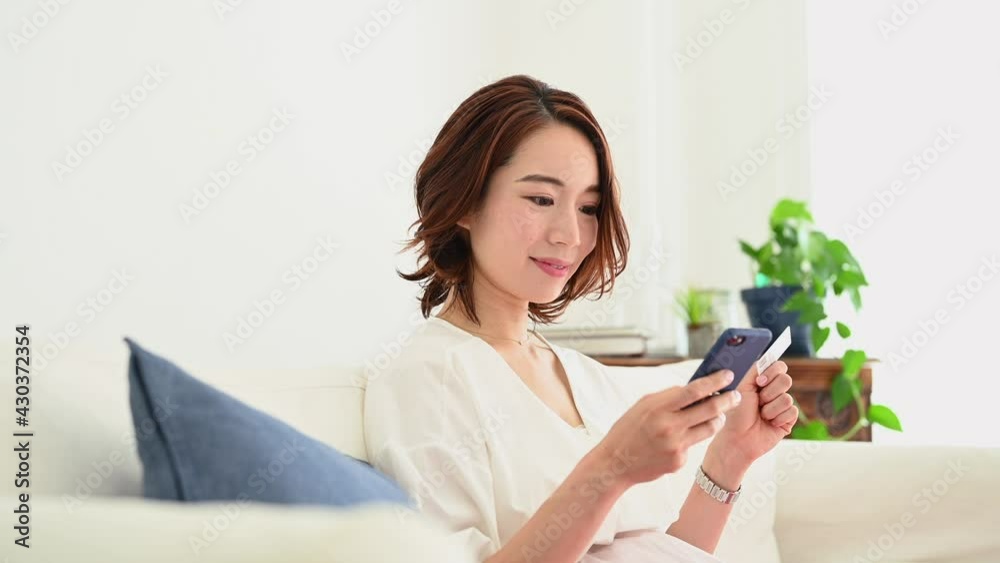 ソファーに座ってスマートフォンを操作する妊娠している女性 ソファーに座ってスマートフォンを操作する妊娠している女性