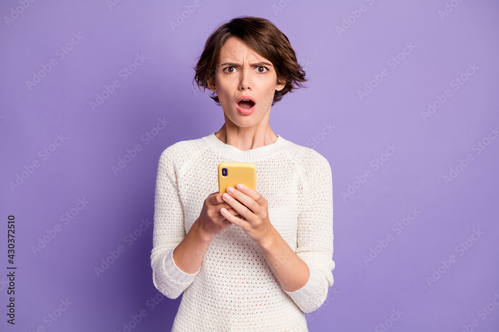 Photo portrait of angry misunderstanding female student reading fake news cellphone isolated on bright purple color background Photo portrait of angry misunderstanding female student reading fake news cellphone isolated on bright purple color background