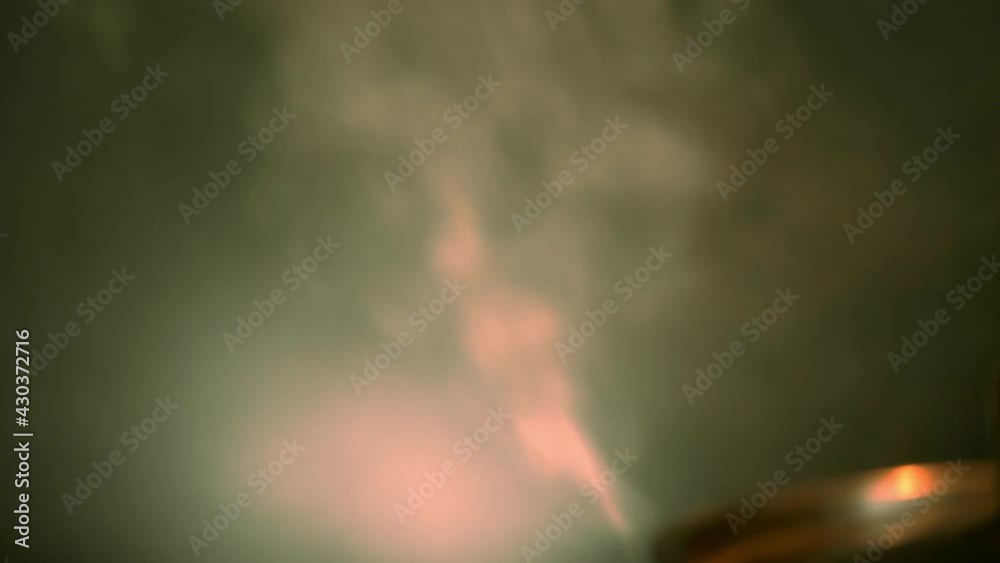 Closeup of cooking pot releasing colorful stream in unconventional lightning Closeup of cooking pot releasing colorful stream in unconventional lightning