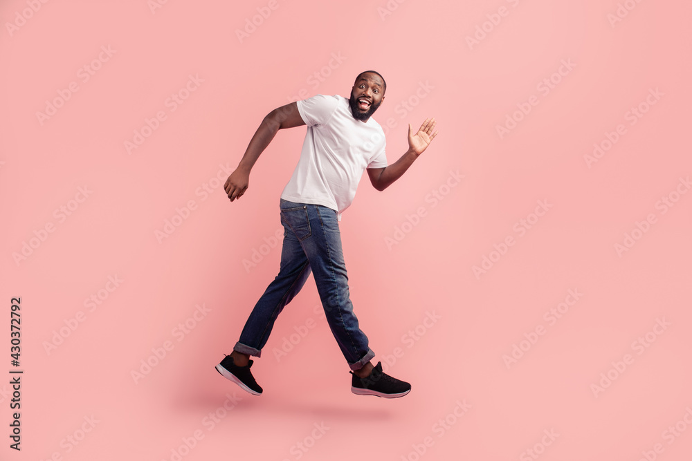 Portrait of sporty energetic man jumping run on pink background
