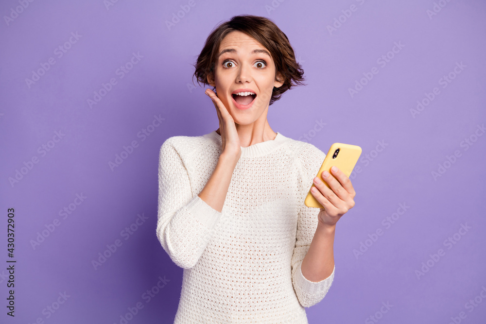 Photo portrait of girl with bob hair amazed surprised touching cheek with cellphone isolated on pastel violet color background Photo portrait of girl with bob hair amazed surprised touching cheek with cellphone isolated on pastel violet color background