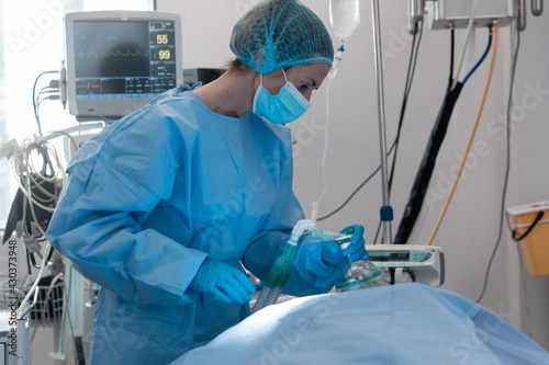 Caucasian female surgeon wearing face mask putting oxygen mask on patient lying in bed