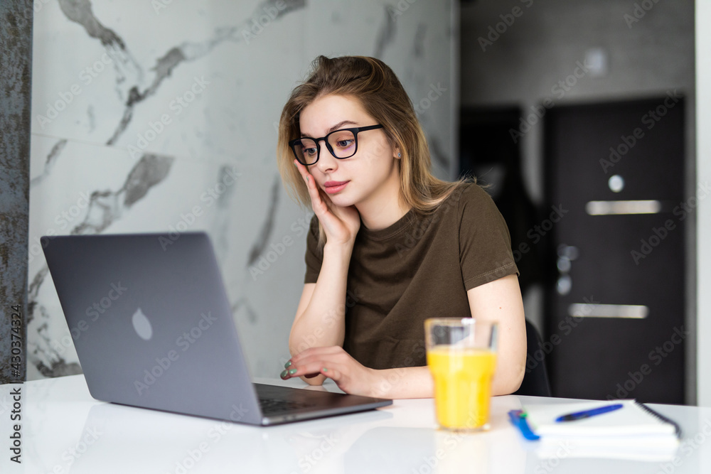 Beautiful young woman using laptop computer in the kitchen. Beautiful young woman using laptop computer in the kitchen.