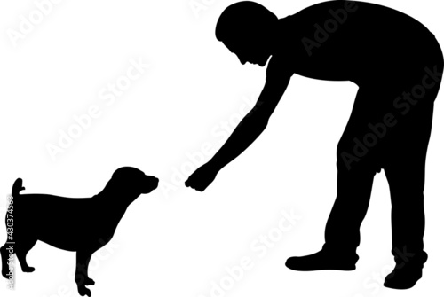 silhouette of man feeding a dog