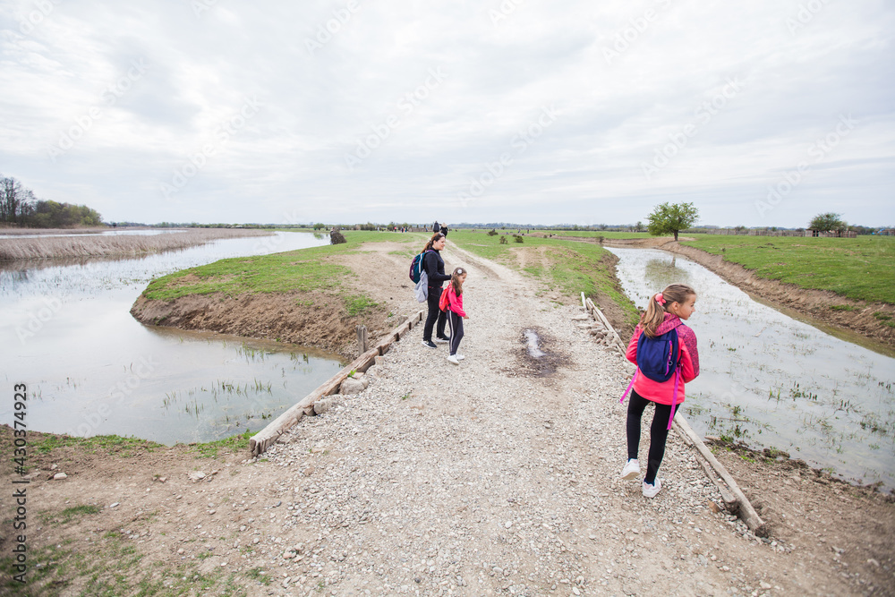 Family relax in nature reserve, mother with daughters walking in nature, spring landscape.