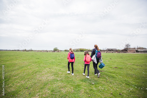 Family relax in nature reserve, mother with daughters walking in nature, spring landscape.