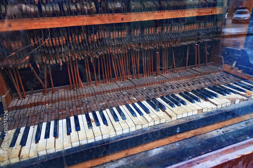 View from the street through the glass on the old vintage piano in ruined condition.