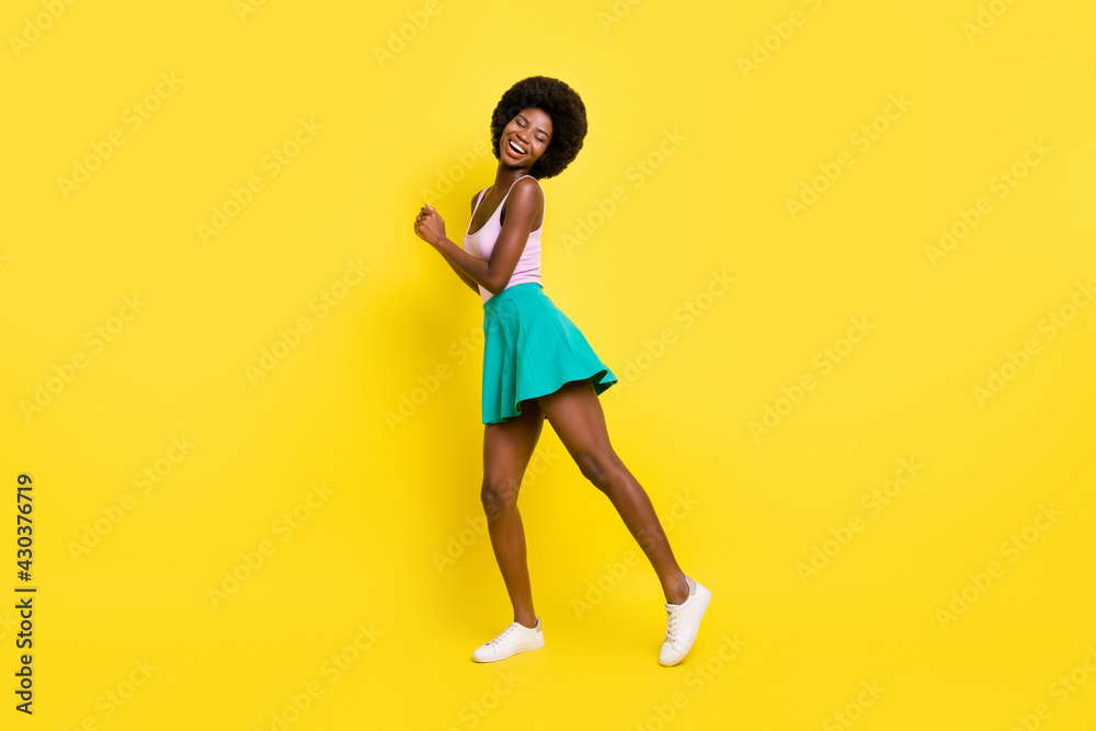 Full size photo of dark skin woman dance closed eyes wear green short skirt isolated on yellow color background
