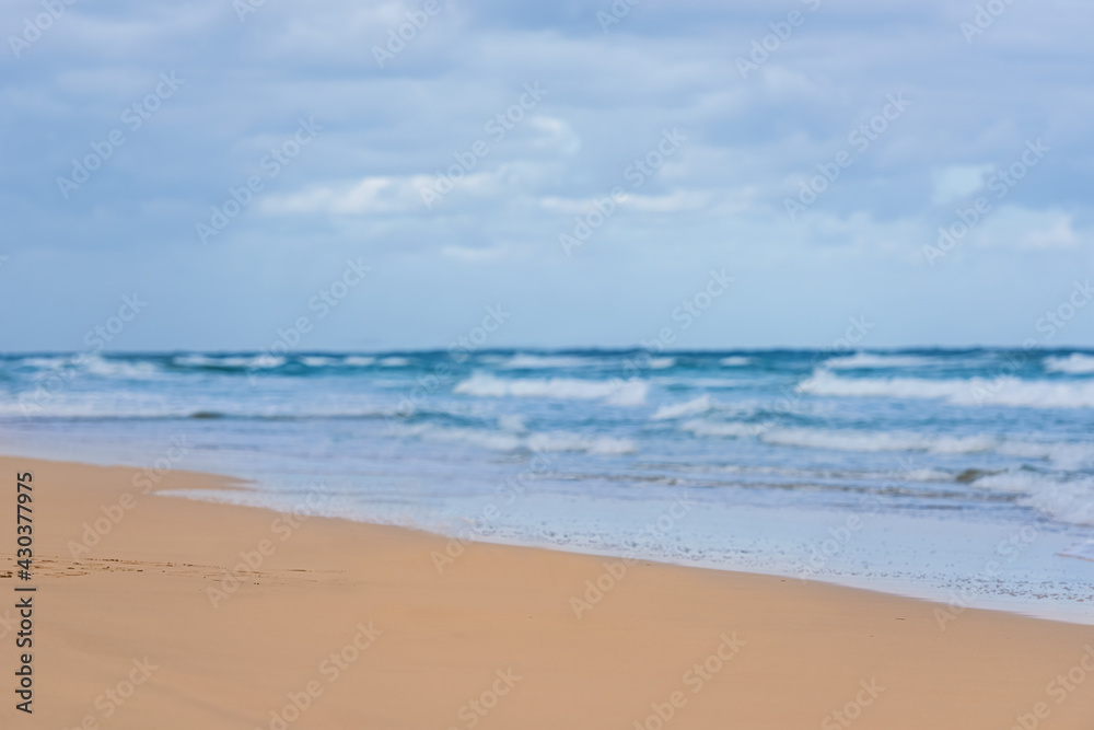 Tropical ocean beach with sky and clouds on the horizon. The surf of the waves ashore, the fine yellow sand at the water