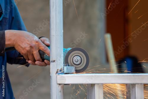 The welded iron fence is adorned with electric grinding wheels. There is a spark from the polishing. The job collection of the steel welder