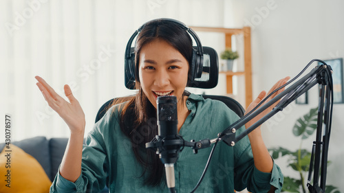 Bild auf Leinwand Happy asia girl record a podcast with headphones and microphone look at camera  talk and take a rest in her room