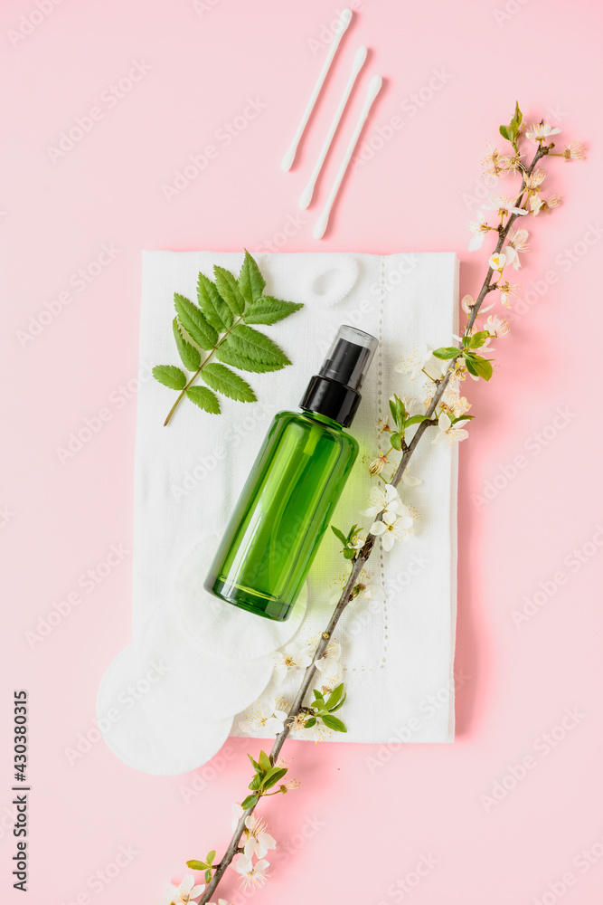 Kosmetik Artikel und eine grüne Parfüm Flasche auf einem weißen Handtuch. Pinker Hintergrund, Flat lay. Kosmetik Artikel und eine grüne Parfüm Flasche auf einem weißen Handtuch. Pinker Hintergrund, Flat lay.