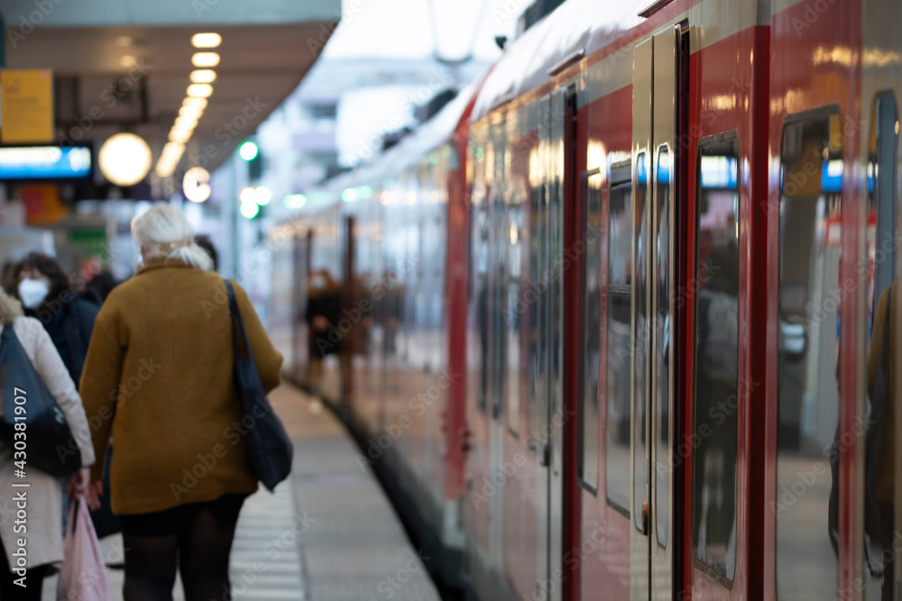 Menschen mit Masken am Bahngleis im Hauptbahnhof Köln bei der Einfahrt des Zuges