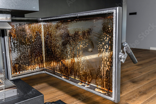 Cleaning the corner glass from soot in a modern fireplace with a closed combustion chamber standing in the living room, painted black. photo