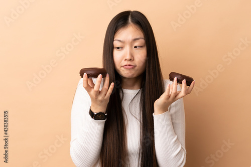 Young Chinese girl over isolated background holding donuts