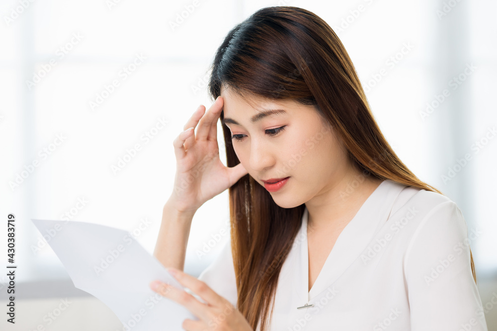 Young asian business woman hand touching head looking at paper work or bills she's feeling depressed stress headache be tired from working with laptop a long time she symptom office syndrome. Young asian business woman hand touching head looking at paper work or bills she's feeling depressed stress headache be tired from working with laptop a long time she symptom office syndrome.