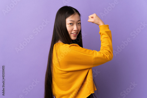 Young Chinese girl over isolated purple background doing strong gesture