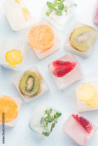 Fresh, summer background with frozen ice cubes with fruits, berries, herbs on a white background. Freezing is a safe method. Home food concept
