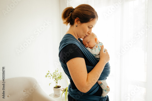 Attachment parenting concept. Young mother with baby in sling photo