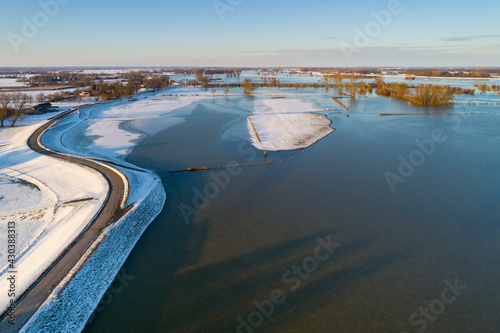 Aerial view of snow-covered dike with road on top along flooded floodplains of river IJssel in winter, Overijssel, Netherlands. photo