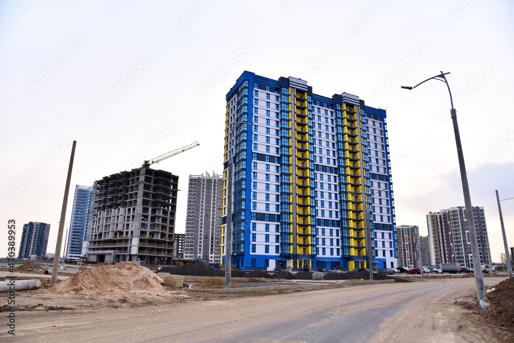 Facade of a new modern high-rise residential building. Tower crane on construction of a residential building. Cranes on formworks. Realtor and Real Estate. Construction the building